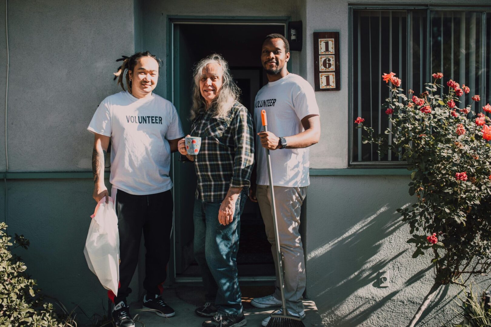 Three people standing in front of a building with skateboards.