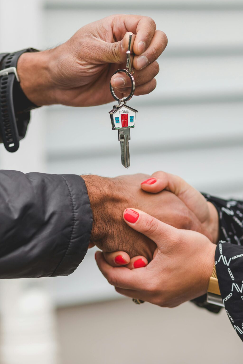 A man and woman shaking hands over keys.